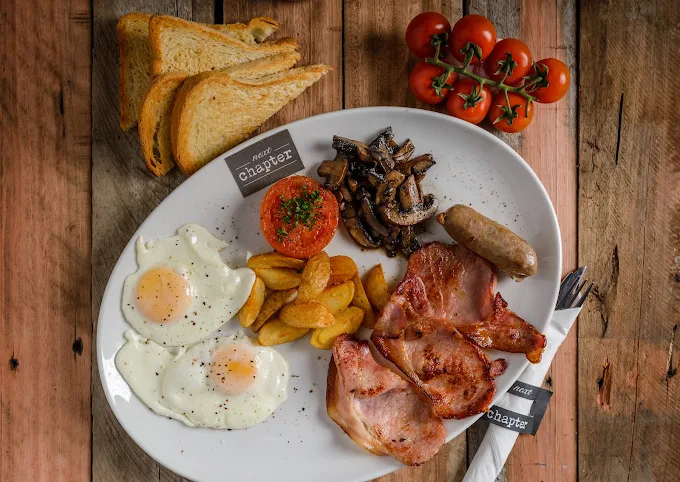 Full breakfast plate with eggs, bacon, grilled tomato, mushrooms, toast and cherry tomatoes on the vine