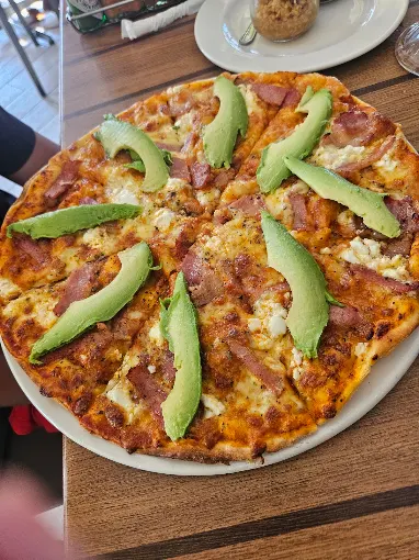 Wood-fired pizza topped with shredded chicken and fresh avocado
